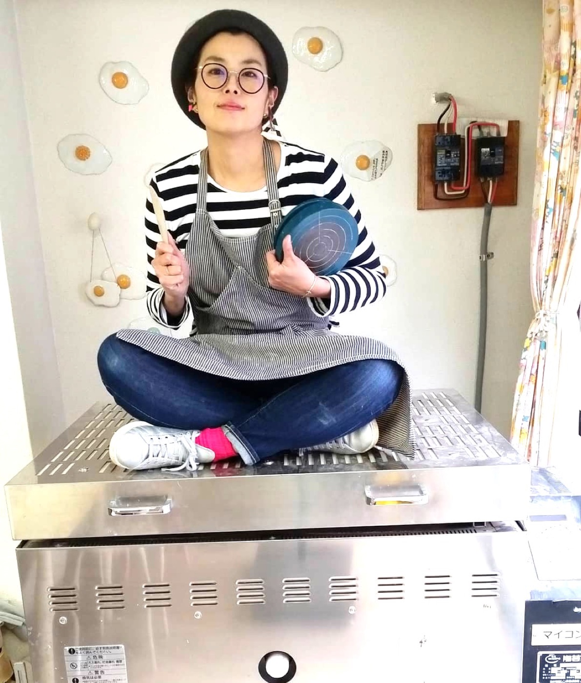 卵焼きの壁飾りの前でポーズをとる講師