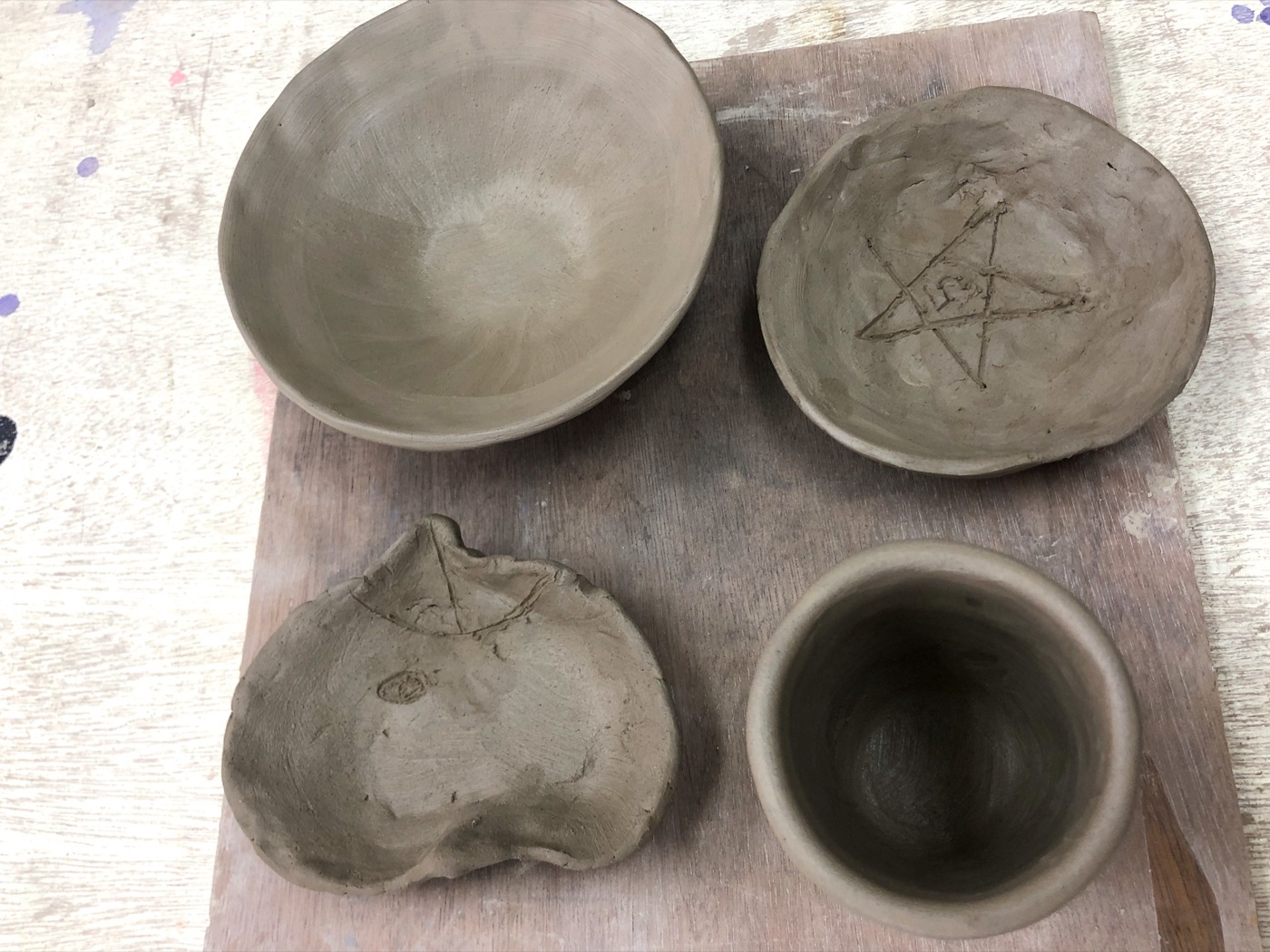 焼成前の粘土作品4点。星のマークや動物の顔が刻まれている